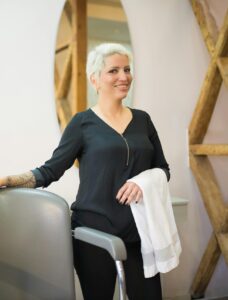 Hair stylist standing confidently in a contemporary salon, ready to serve clients.